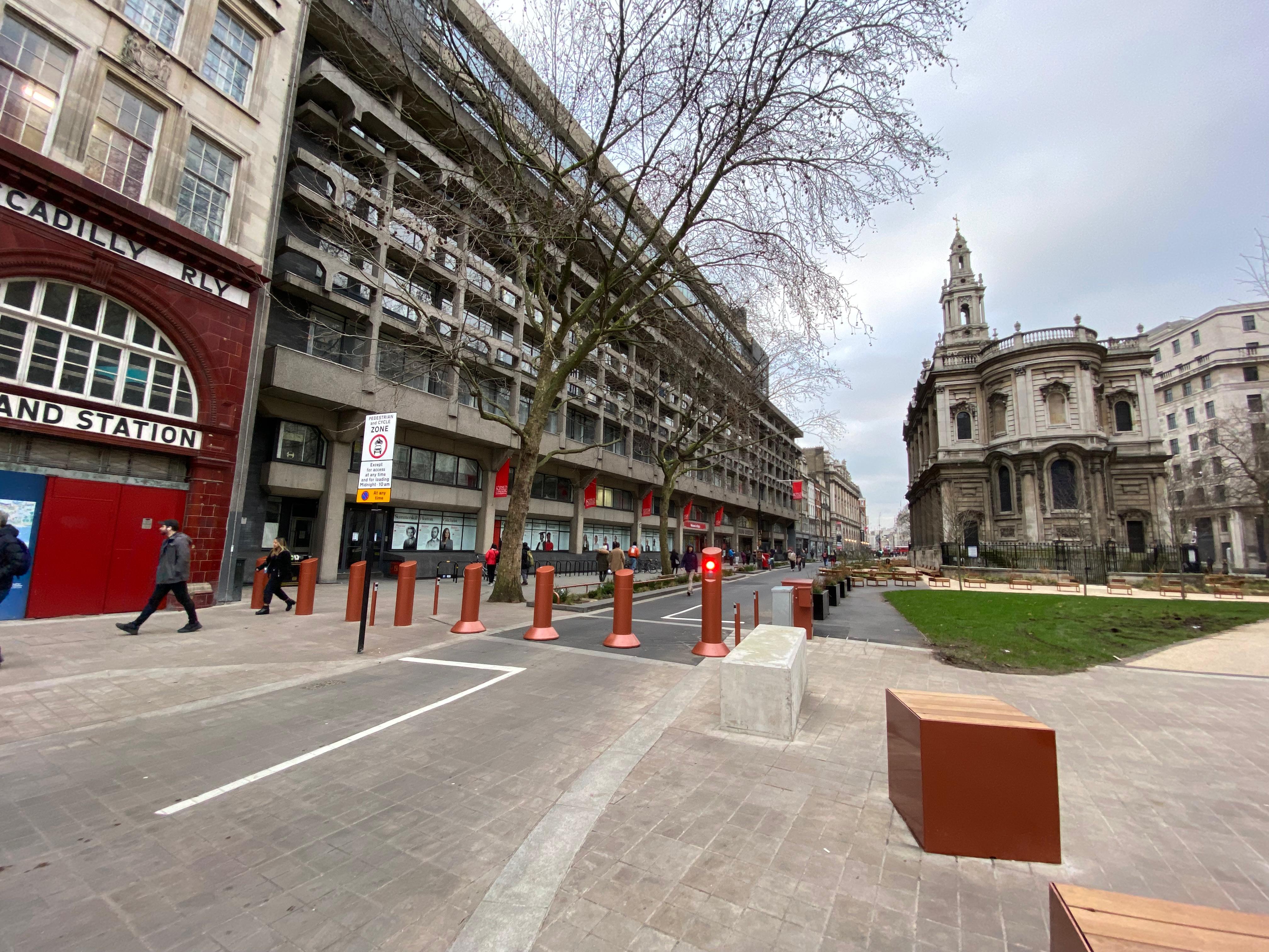 Bollards seperate a pedestrian area from a road. They are in orange and stand out from the road surface