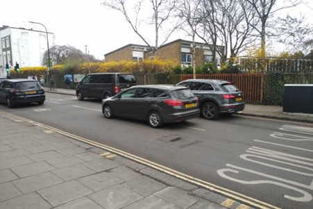 Street with parked cars in front of the school 