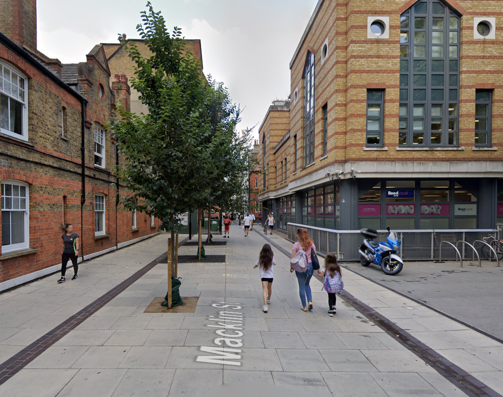 People walking down Macklin Street with a row of trees